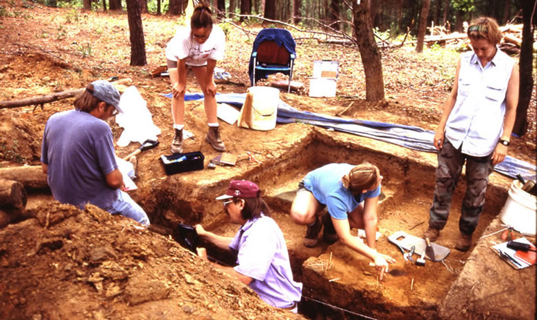 Archeologists from Texas A&M excavating in the area of a possible latrine. Dr. Alston Thoms, project director, is shown in trench in foreground. Photo by Steve Black.