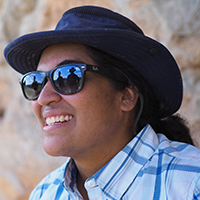 A photograph of a smiling woman wearing sunglasses