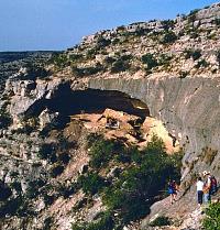 Early morning excavations get underway at Baker Cave, a large rockshelter located in a side canyon of the Devils River. Archeologists gingerly make their way down the steep rocky slope to the relative safety of the cave. Photo by Tom Hester.