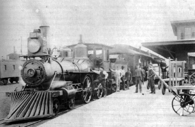 black and white photo of a train at a train station
						